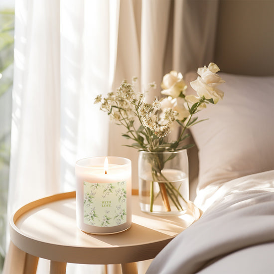 a white candle sitting on top of a table next to a vase of flowers